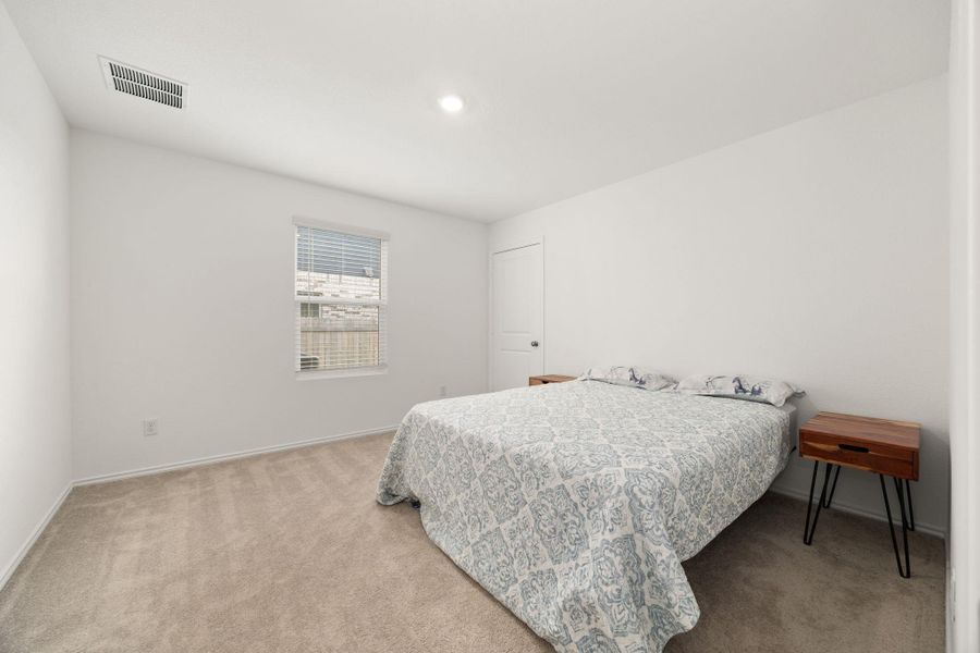 A comfortable bedroom with soft carpet flooring and a single window offering natural light.
