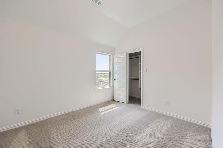 Secondary bedroom with a closet, vaulted ceiling, and light carpet