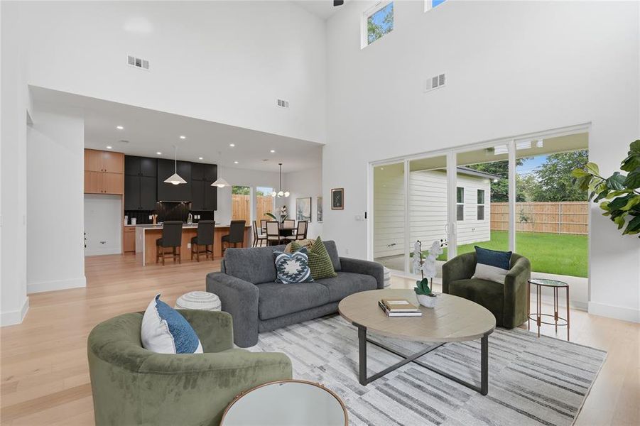 Vaulted ceilings enhance the main living area, featuring light wood-finish flooring, recessed lighting, and a multi-panel sliding glass door opening to the backyard Vaulted ceilings enhance the main living area, featuring light wood-finish flooring, recessed lighting, and a multi-panel sliding glass door opening to the backyard