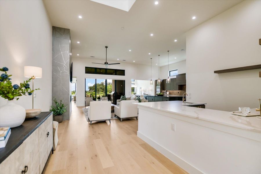 An open concept living area boasts light wood flooring and modern recessed lighting, leading to a gourmet kitchen.