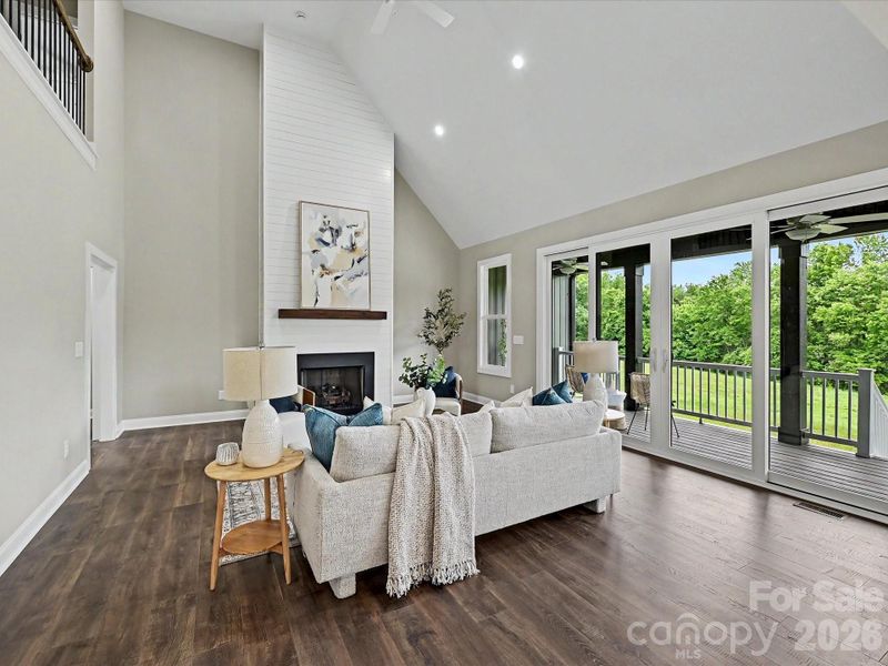 The stunning great room showcases soaring vaulted ceilings, expansive windows with scenic views, cozy gas fireplace and an open-concept layout that seamlessly connects the living, dining, and kitchen spaces for effortless entertaining.