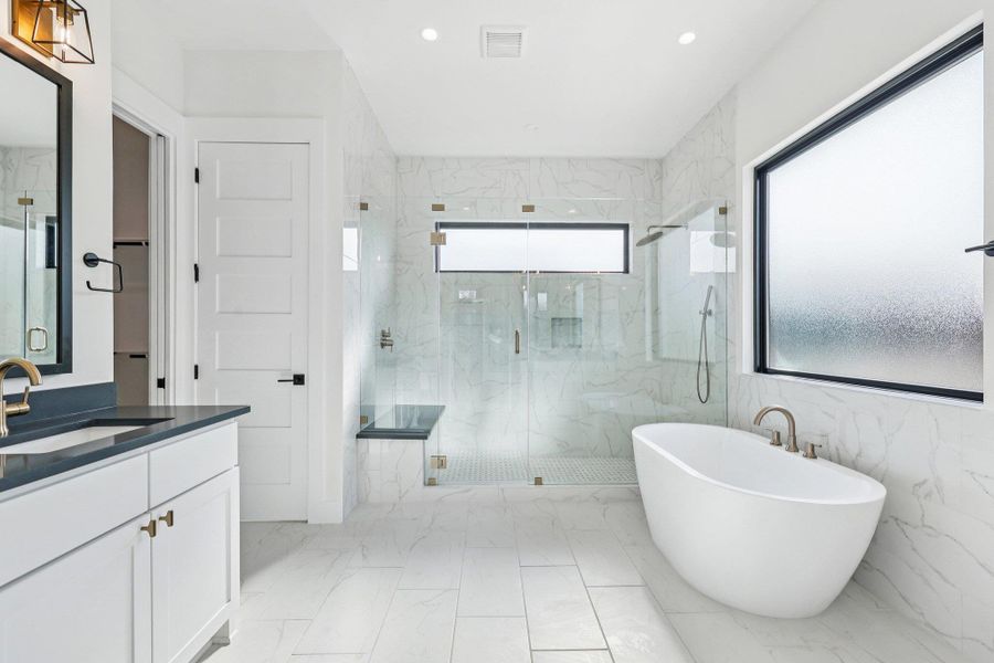 Bathroom with a freestanding bath, light marble finish floors, a marble finish shower, vanity, and recessed lighting