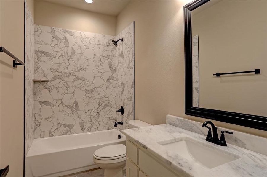 Full bathroom with tiled shower / bath, vanity, and toilet