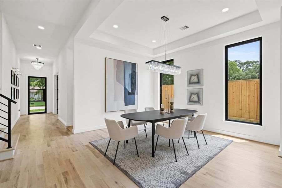 Elegant dining room with sleek chandelier, and large windows, perfect to host gatherings in a bright, inviting space.