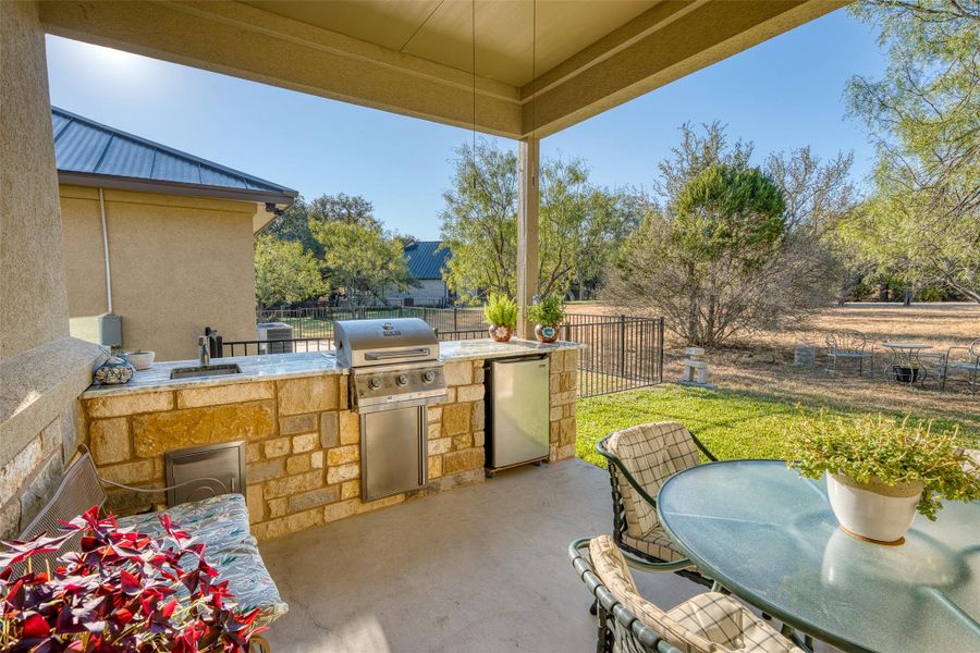 Fenced backyard with outdoor dining space, a patio area, exterior kitchen, and a ceiling fan