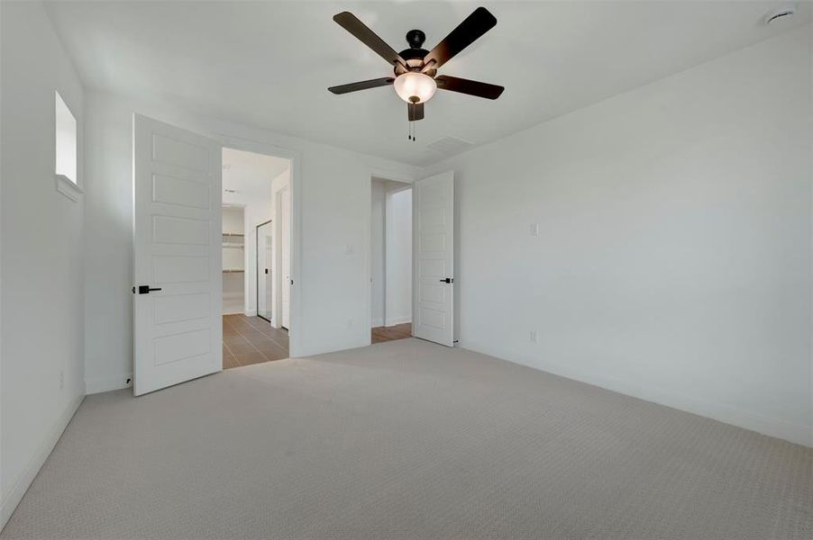 Unfurnished bedroom with light carpet and a ceiling fan