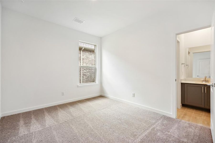 Unfurnished bedroom featuring ensuite bath, sink, and light carpet