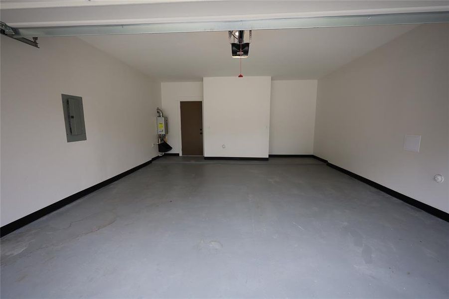 Garage featuring baseboards and electric panel