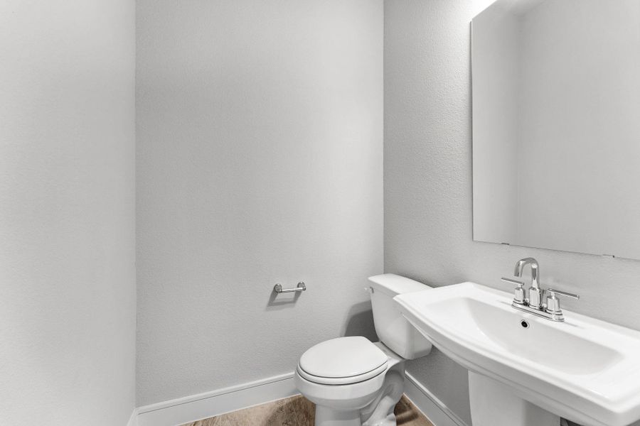 A compact powder room with a sleek pedestal sink and contemporary fixtures awaits guests. A compact powder room with a sleek pedestal sink and contemporary fixtures awaits guests.