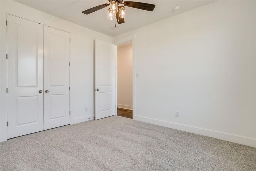 Unfurnished bedroom featuring carpet, ceiling fan, and a closet Unfurnished bedroom featuring carpet, ceiling fan, and a closet
