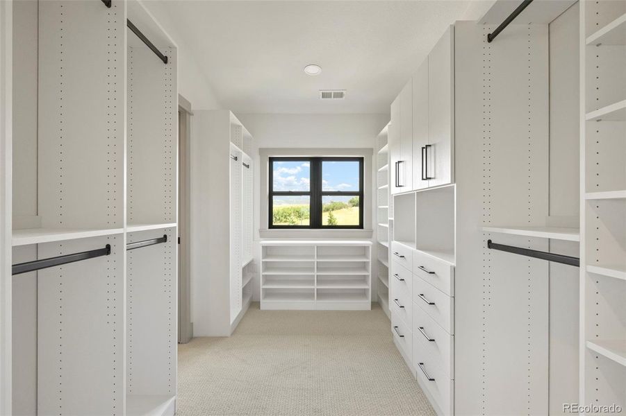 Primary bedroom walk-in closet with custom cabinetry