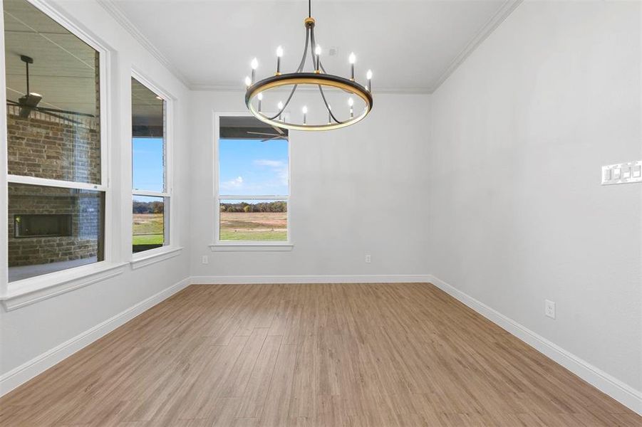 Spare room featuring crown molding, an inviting chandelier, and light wood-type flooring