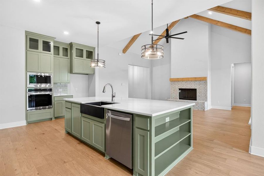 Modern kitchen featuring green cabinetry, stainless steel appliances, and a central island with a white countertop and black farmhouse sink Modern kitchen featuring green cabinetry, stainless steel appliances, and a central island with a white countertop and black farmhouse sink