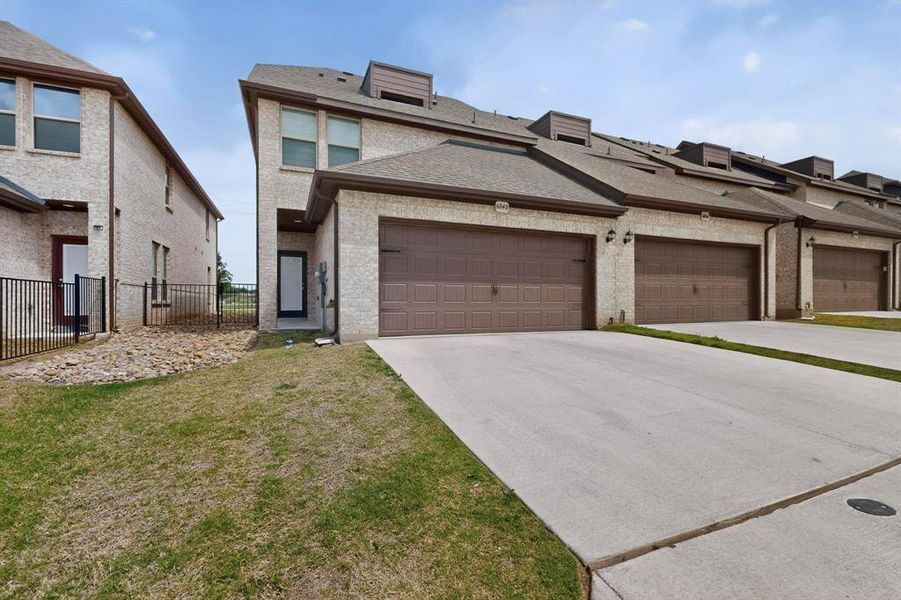 The property features a light-colored brick exterior with brown garage doors and a paved driveway