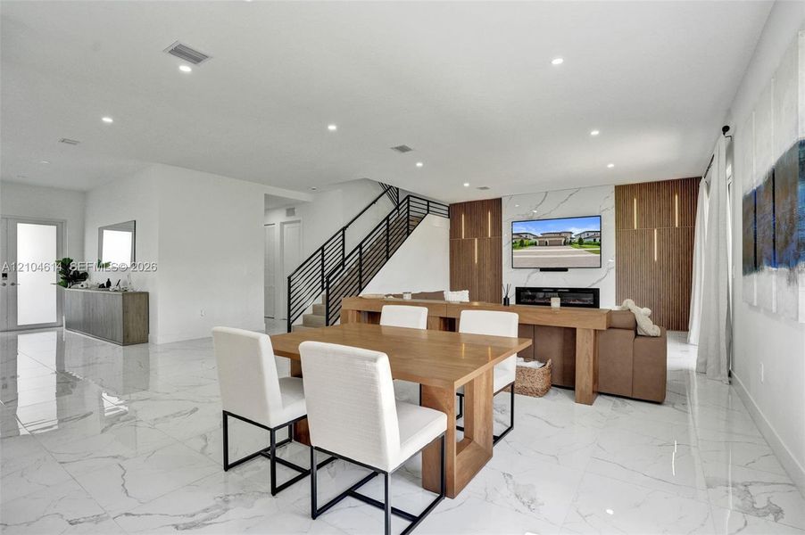 Recessed lighting illuminates the open-concept living space with white walls and large format tile flooring