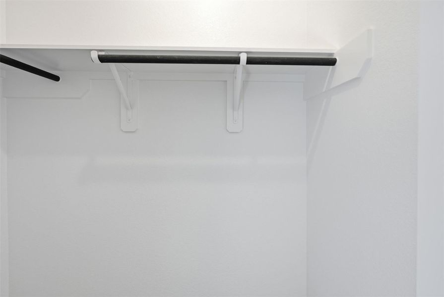 Spacious walk-in closet with dual hanging rods for ample storage.