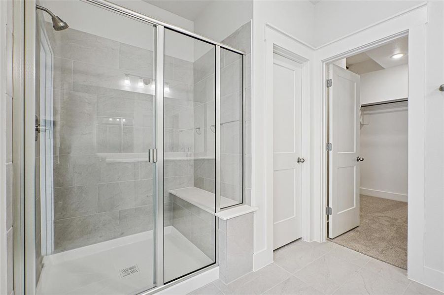 Full bath with a stall shower, a walk in closet, and tile patterned flooring