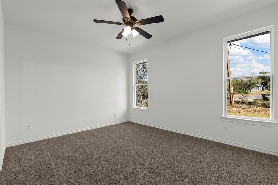 Unfurnished room featuring dark carpet and ceiling fan