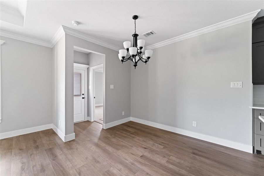 Unfurnished dining area with ornamental molding, dark wood finished floors, and a chandelier