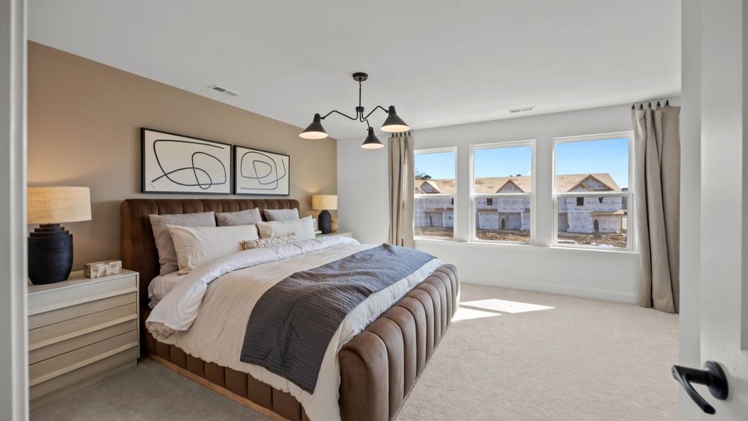 The Rochester Plan by DRB homes spacious & cozy primary bedroom with large windows letting in natural light in Charlotte, NC.