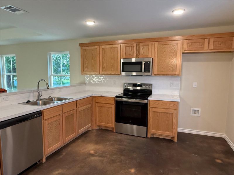Kitchen featuring stainless steel appliances, concrete floors, light countertops, and recessed lighting Kitchen featuring stainless steel appliances, concrete floors, light countertops, and recessed lighting