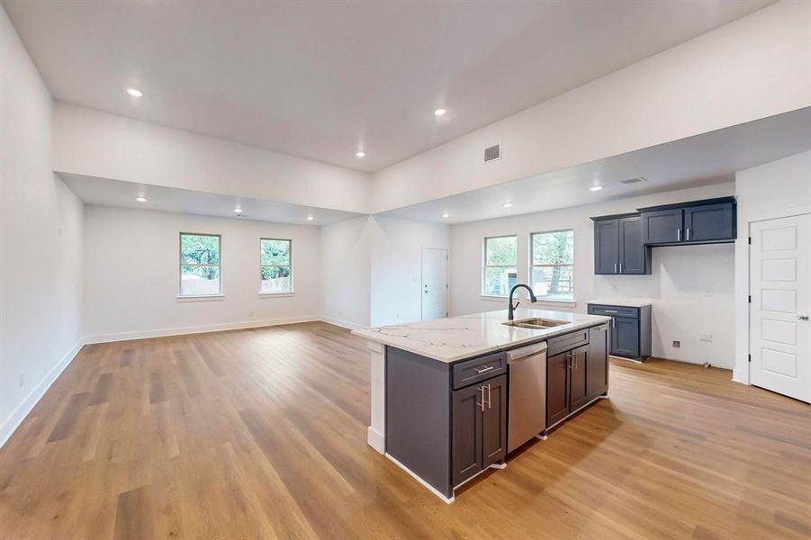 Kitchen featuring stainless steel dishwasher, a healthy amount of sunlight, a center island with sink, and sink