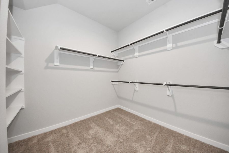 Walk-in closet that epitomizes luxury and practicality. This generously sized space features built-in shelving, offering abundant room for impeccable organization. High ceilings and recessed lighting create a bright and welcoming ambiance. Sample photo of completed home with similar floor plan. Actual colors and selections may vary.