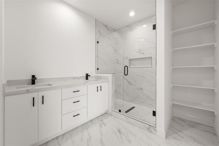 Full bathroom with marble finish flooring, a marble finish shower, double vanity, and recessed lighting Full bathroom with marble finish flooring, a marble finish shower, double vanity, and recessed lighting