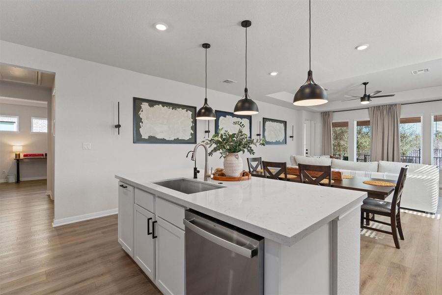 Kitchen featuring stainless steel dishwasher, open floor plan, decorative light fixtures, and light wood-style floors