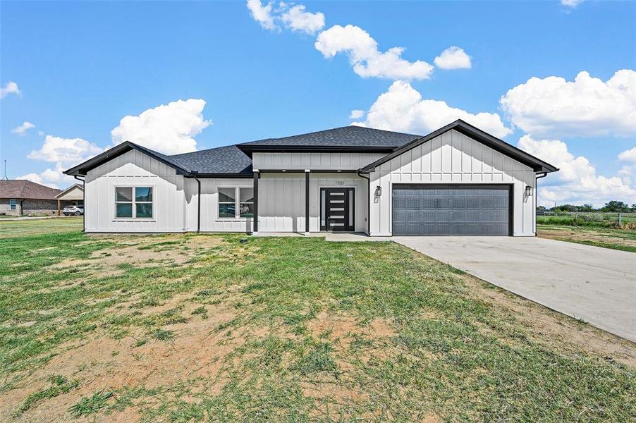 Modern farmhouse style home with a garage and a front yard