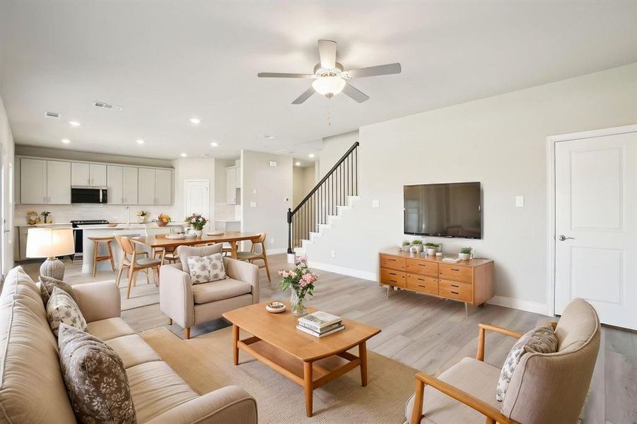 Living room with light wood-style floors, recessed lighting, a ceiling fan, and stairway Living room with light wood-style floors, recessed lighting, a ceiling fan, and stairway