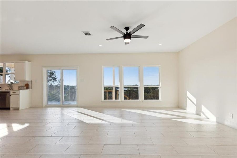 Unfurnished living room with a healthy amount of sunlight, ceiling fan, and light tile patterned floors