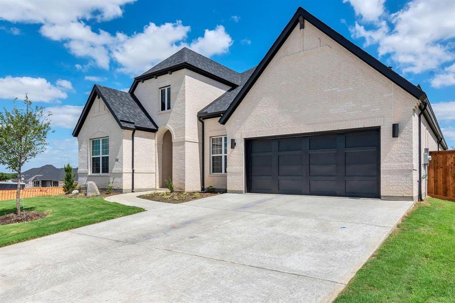 French country home featuring a garage and a front yard