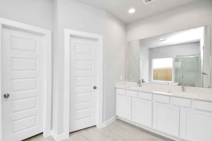 Escape to a spa-like oasis in this primary bathroom. Enjoy a walk-in shower with tile surround, a separate garden tub with custom detailing, and an elegant vanity featuring light countertops, modern hardware, and beautiful recessed lights. Experience luxury and relaxation in every detail. Sample photo of completed home with similar floor plan. Actual colors and selections may vary.