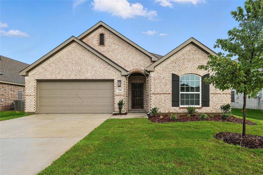 French country inspired facade with brick siding, a garage, a front lawn, and concrete driveway