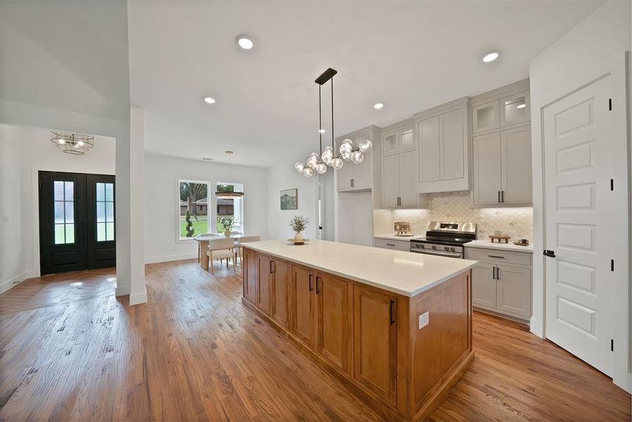 Kitchen with a chandelier, electric stove, backsplash, a center island, and decorative light fixtures Kitchen with a chandelier, electric stove, backsplash, a center island, and decorative light fixtures