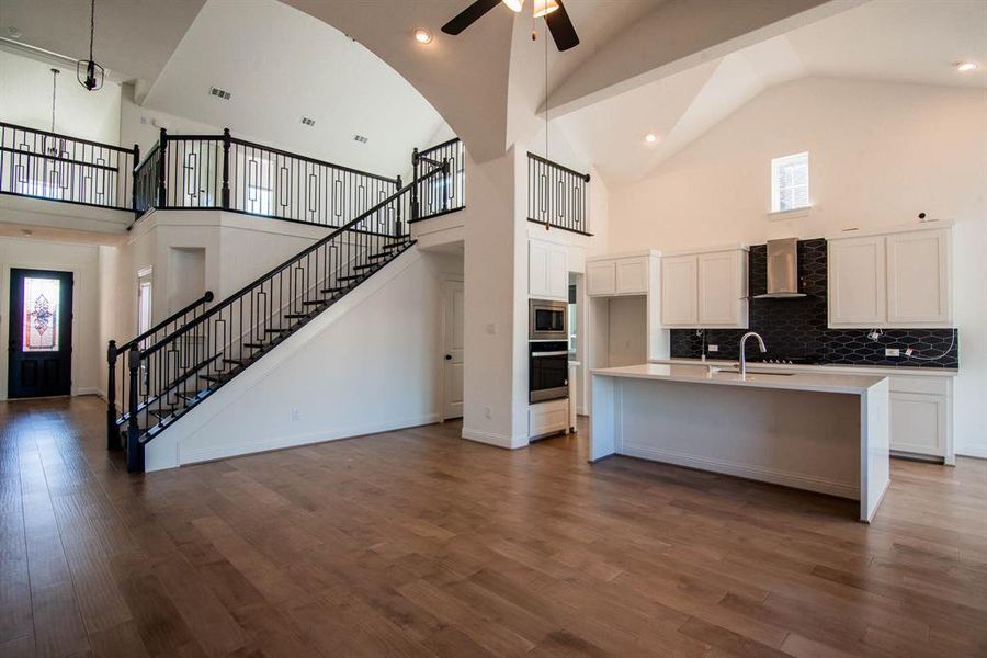 Kitchen featuring dark hardwood / wood-style floors, stainless steel appliances, and high vaulted ceiling