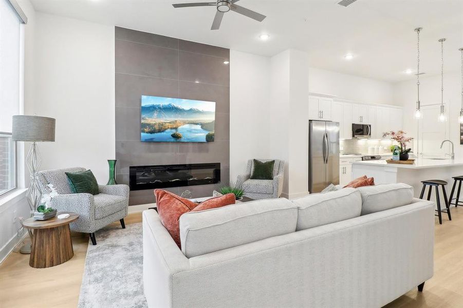 Living area featuring light wood-style floors, a large fireplace, visible vents, and a ceiling fan