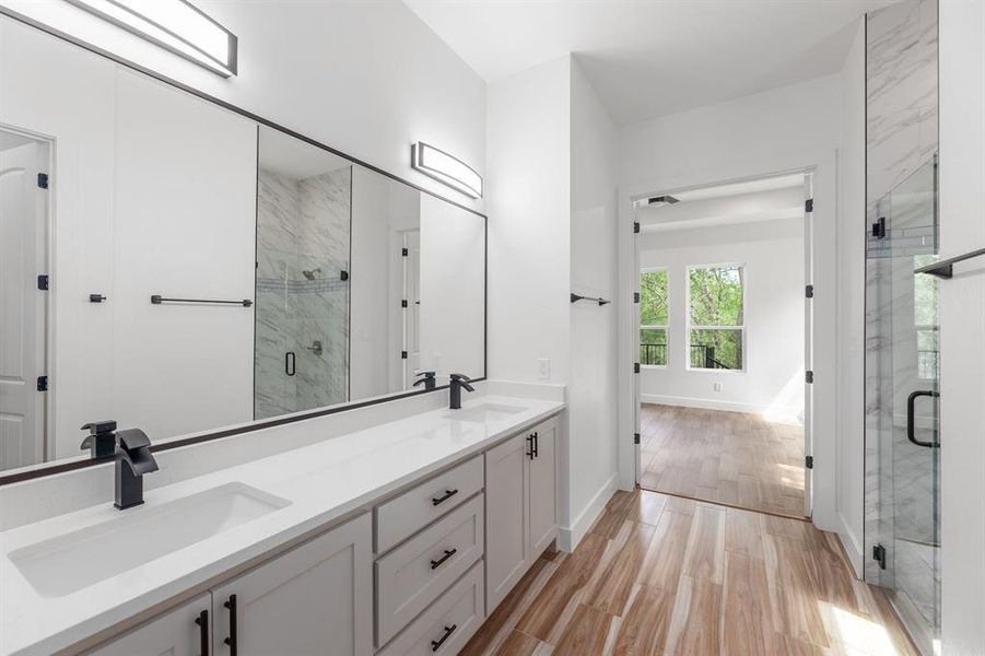 Bathroom with a sink, double vanity, wood finished floors, and a shower stall