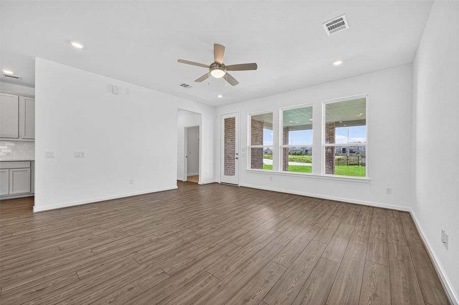 This bright living space features expansive windows that showcase views of the backyard and covered patio, filling the room with natural light and charm.