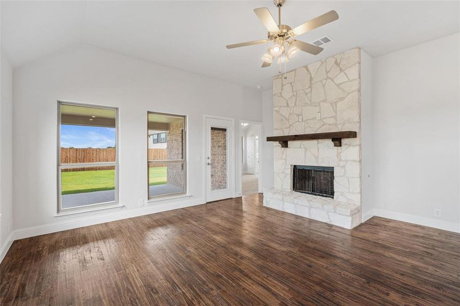 Unfurnished living room with dark wood-style floors, a fireplace, vaulted ceiling, and ceiling fan