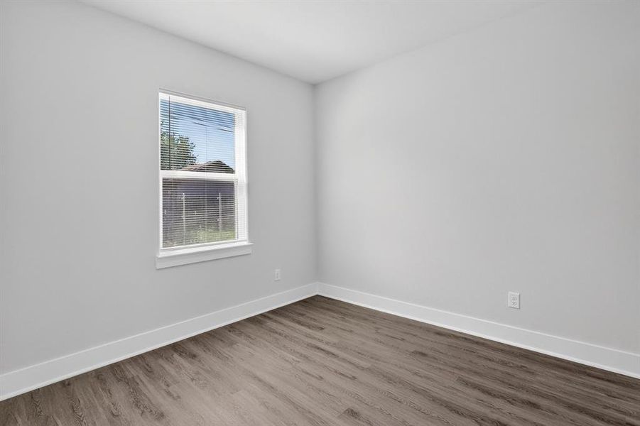 Light-filled interior space featuring wood-finish flooring, white baseboards, and a window with horizontal blinds