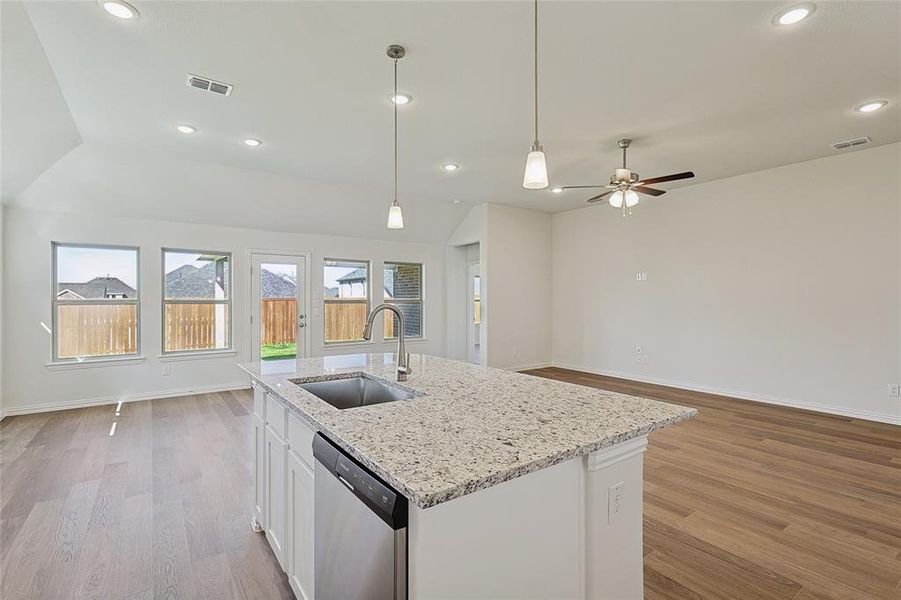 Kitchen featuring an island with sink, white cabinetry, stainless steel dishwasher, light hardwood / wood-style flooring, and sink