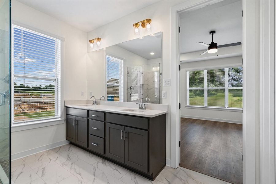 Modern bathroom featuring a dual vanity with dark cabinetry, white countertops, and brushed nickel fixtures Modern bathroom featuring a dual vanity with dark cabinetry, white countertops, and brushed nickel fixtures
