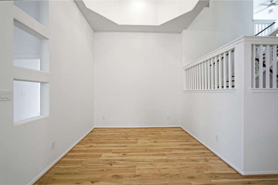 Spare room featuring light wood-type flooring, plenty of natural light, a high ceiling, and a ceiling fan