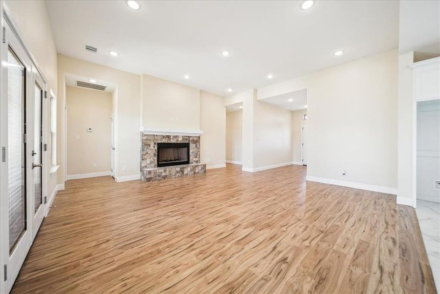 Unfurnished living room with a stone fireplace and light hardwood / wood-style flooring