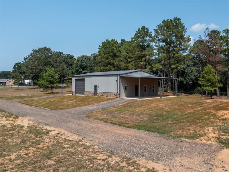 View of front of property featuring an outbuilding, dirt driveway, and a front lawn