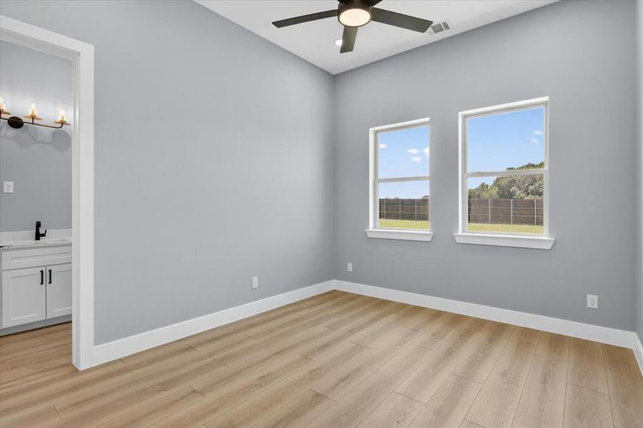 Spacious room featuring wood-finish flooring, light grey walls, and two large windows
