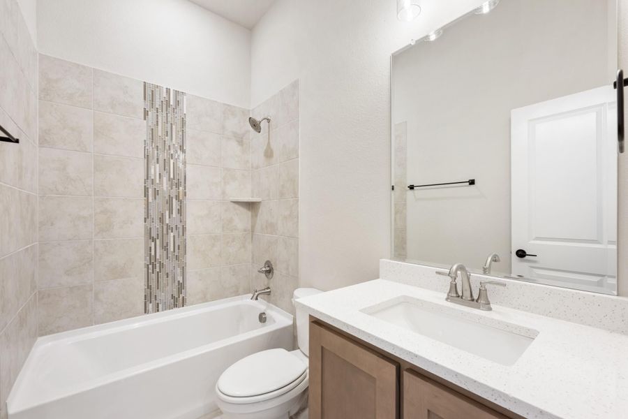 Bathroom with tiled tub-shower combo, white quartz vanity, and mosaic tile accent strip