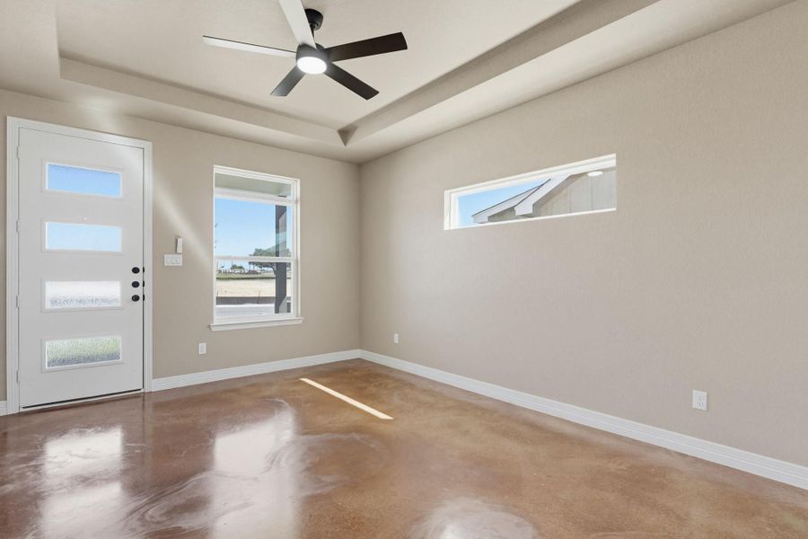 Foyer entrance featuring concrete floors, healthy amount of natural light, a ceiling fan, and a tray ceiling